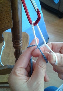 Untie the blue, adjust the strings on the hook so that the start of the blue and the bottom of the white plaiting are even and get ready to plait the blue and the white together