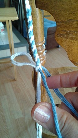 Secure the white strings, with a knot or a twist tie, and plait the blue strings 13 times
